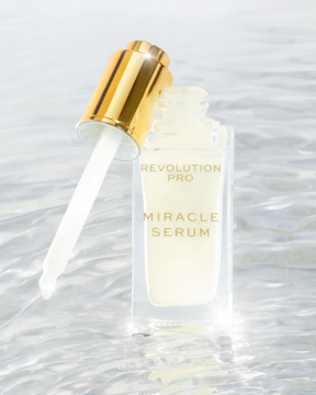 Revolution PRO Miracle Serum w przezroczystej butelce z wyciągniętym złotym zakraplaczem, na tle wody.