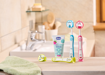 Chicco: dwie szczoteczki dla dzieci (niebieska, różowa hippo/panda) i truskawkowa pasta na łazienkowej półce.