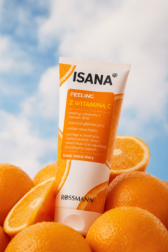 Isana Peeling z Witaminą C w białej tubce, wśród pomarańczy, na tle błękitnego nieba. Chemiczny z BHA.