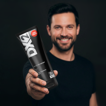 Uśmiechnięty mężczyzna prezentuje czarną tubę szamponu DX2 przeciw wypadaniu włosów, logo wyraźne.