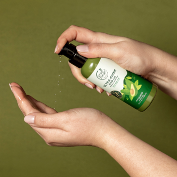 Ręce spryskują Olej do włosów Petal Fresh z awokado z zielonej butelki z pompką. Nawilża, nadaje blask.