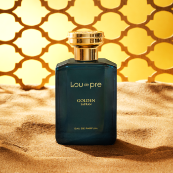 Lou De Pre Golden Safran, męska woda perfumowana, butelka granatowa ze złotym korkiem na piasku, tło w złote wzory.