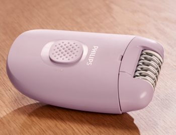 Różowy depilator elektryczny Philips Series 2000 z głowicą depilującą, leży na drewnianym tle.