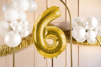 Złoty balon foliowy urodzinowy cyfra 6, satynowy, na tle białych balonów i różowej ściany, widok z przodu.