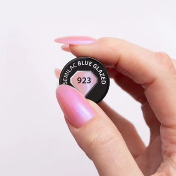 Dłoń trzyma nakrętkę lakieru hybrydowego Semilac Blue Glazed 923, paznokcie z perłowym różowym wykończeniem.