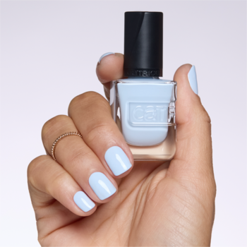 Ręka z paznokciami pomalowanymi na jasnoniebiesko trzyma lakier Catrice Gel Affair w odcieniu Blue You a Kiss.