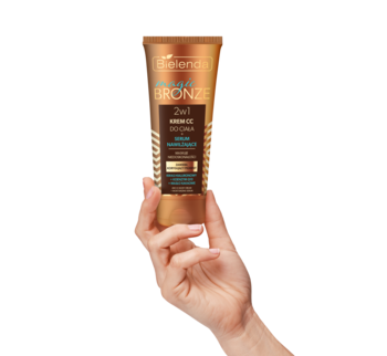 Ręka trzyma złotą tubkę Bielenda Magic Bronze Krem CC do ciała 2w1 z kryjącym fluidem i serum nawilżającym.