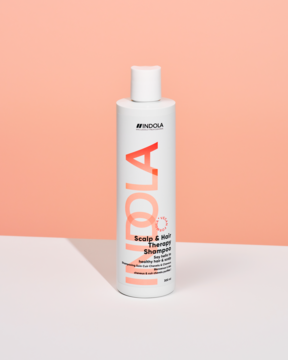Indola Scalp & Hair Therapy wegański szampon, biała butelka z pomarańczowym napisem, widok z przodu na pastelowym tle.