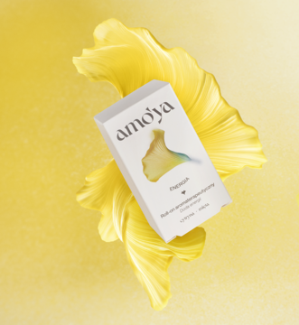 Biały roll-on aromaterapeutyczny Amo'ya Energia Fresh na tle żółtych, stylizowanych liści ginkgo.