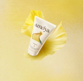 Amo'ya serum do ciała Energia, biała tubka z żółtą grafiką, widok z góry na pofałdowanym żółtym tle. Lekkie z kofeiną.