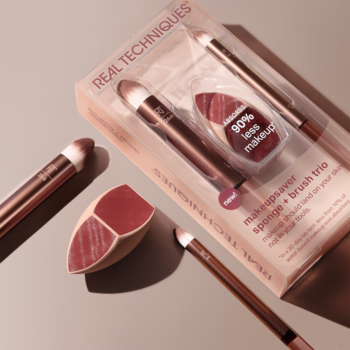 Zestaw Real Techniques Makeupsaver: różowo-złote pędzle i gąbka, widoczne w opakowaniu i luzem, na beżowym tle.
