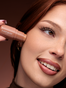 Kremowy bronzer w sztyfcie Everybody London Light-Medium aplikowany na policzek kobiety, naturalne konturowanie.