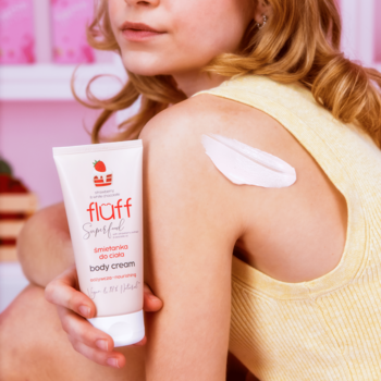 Fluff Superfood truskawka biała czekolada body-cream. Biała tubka i gęsty krem na ramieniu osoby.