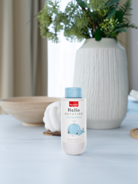 Biała butelka Fisher Price Hello Bath Time z niebieską nakrętką i wielorybem, płyn do kąpieli dla dzieci, na stole.