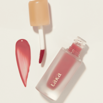 Pomadka w płynie Laka Fruity Glam Tint Humming, widok z góry flakonu, aplikatora i lśniącej różowej smugi.