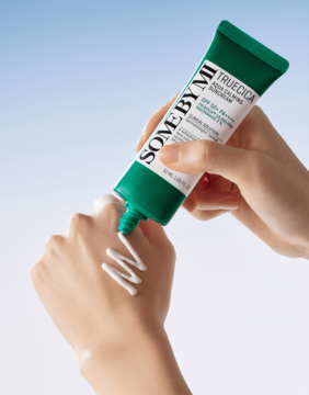 Krem SOME BY MI Truecica Aqua Calming Sunscreen SPF 50+ w zielonej tubce, wyciskany na dłoń, biała smuga.