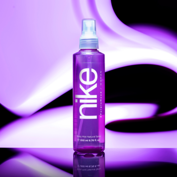 Nike #PurpleMood Woman Body Mist w przezroczystej, fioletowej butelce, na tle purpurowych fal.