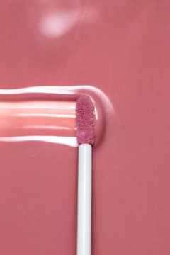 Nawilżający błyszczyk Dessi Creamy Cover Lip Tint Candy. Aplikator tworzy gładką, lśniącą smugę na różowym tle.