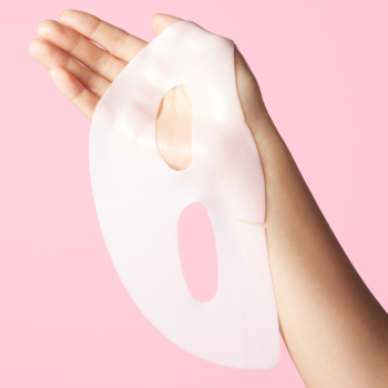 Holika Holika The Real Gel Mask Collagen, przezroczysto-różowa maska hydrożelowa, trzymana w dłoni na różowym tle.