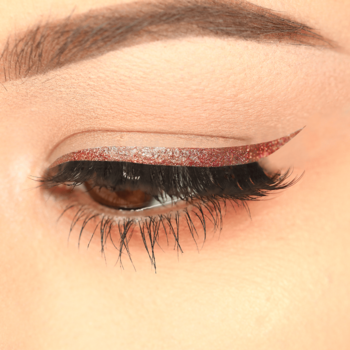Zbliżenie na oko z brokatowym eyelinerem J.Cat Beauty Rock Glitz Rosy Glam, widoczna precyzyjna kreska.