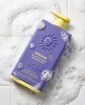 Fioletowy żel pod prysznic MOAN DREAM z żółtą pompką i słońcem, w pianie na białych kafelkach, ujęcie z góry.