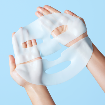 Holika Holika The Real Hyaluronic Gel Mask, nawilżająca hydrożelowa maska, rozłożona w dłoniach na jasnoniebieskim tle.