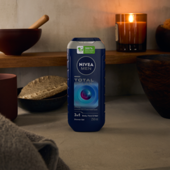 Ciemnoniebieski żel NIVEA MEN Total Relax 3w1 z lawendą na tle relaksującej łazienki ze świecą.