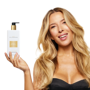 Uśmiechnięta kobieta trzyma żel pod prysznic beBIO Feel The Moment, biała butelka ze złotym detalem, widok z przodu.