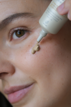 Beżowy podkład Lumene Blur 16h Soft Honey SPF 15 wyciskany z tubki na policzek kobiety. Zbliżenie.