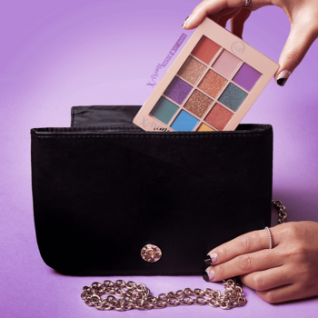 J.Cat Beauty X-treme Access Pocket Shadow, paleta cieni 12 kolorów, wyjmowana z czarnej torebki, fioletowe tło.