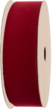 Ciemnoczerwona aksamitna wstążka zwinięta na tekturowej szpuli, widok z boku, miękka faktura.