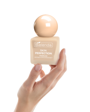 Bielenda Skin Perfection podkład kryjąco-wygładzający w beżowej kwadratowej butelce z okrągłą nakrętką, w dłoni, z przodu.