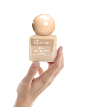 Podkład Bielenda Skin Perfection kryjąco-wygładzający w beżowej butelce, trzymany przez dłoń.