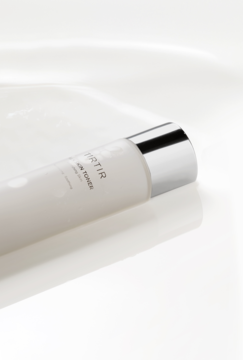 Tonik TIRTIR Milk Skin Toner nawilżający z niacynamidem, biała butelka ze srebrną nakrętką, ukośne ujęcie.