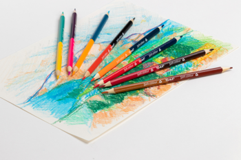 Różnorodne kredki do rysowania w intensywnych kolorach, rozłożone na papierze z kolorowym szkicem, widok z góry.