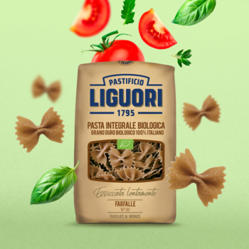 Makaron pełnoziarnisty Farfalle Liguori Integrale BIO w brązowej paczce na zielonym tle z pomidorami i bazylią.