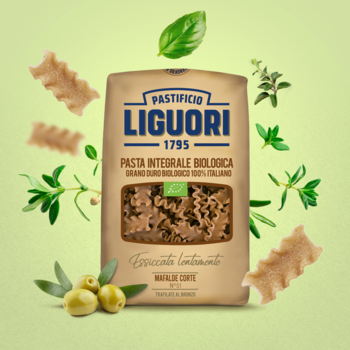 Brązowa paczka makaronu Liguori Mafalde Corte Integrale BIO, otoczona ziołami i oliwkami, na zielonym tle.