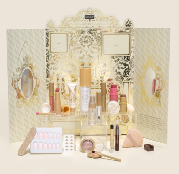 Otwarty Kalendarz Adwentowy Sence Collection z 24 kosmetykami do makijażu i akcesoriami na tle złocistych zdobień.