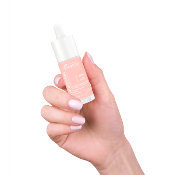 Dłoń z jasnym lakierem trzyma małe, różowe serum kolagenowe Bielenda Revital Derm Prejuvenation z pipetą.