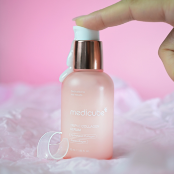 Medicube Triple Collagen Serum 4.0 w matowej różowej butelce z rose gold pompką, dłoń wyciska serum.