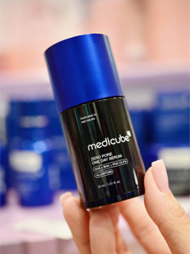 Serum MEDICUBE Zero Pore One Day, czarna butelka z niebieską nakrętką, widoczne logo, trzymane w dłoni, redukujące pory.