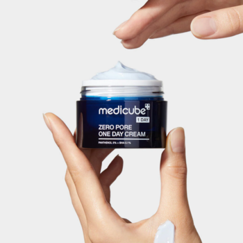 MEDICUBE Zero Pore One Day Cream w granatowym słoiczku, ręce nabierające jasnoniebieski krem nawilżający.