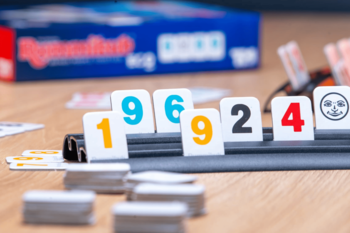 Rummikub Eco gra: zbliżenie na tekturowe kostki z numerami 1, 9, 6, 9, 2, 4 na czarnej podstawce.