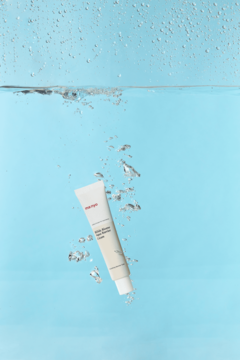 Krem man:yo Bifida Biome Aqua Barrier Cream w białej tubce, zanurzony w błękitnej wodzie z bąbelkami.