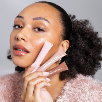 Kobieta prezentuje trzy balsamy Lumene Lip Glow Oil Balm: jasnoróżowy, beżowy i karmelowy.