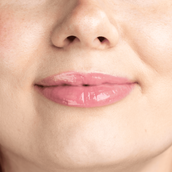 Zbliżenie na usta z Lumene Lip Glow Oil Balm Berry Cream, różowym, lśniącym wykończeniem, podkreślającym naturalny kolor.