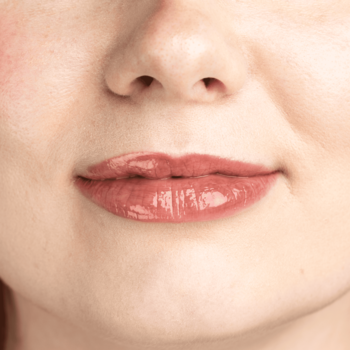 Usta kobiety z błyszczącym Lumene Lip Glow Oil Balm Honey, podkreślającym naturalny kolor i miękkość.