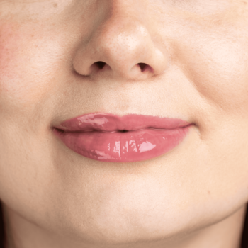 Zbliżenie na usta z Lumene Lip Glow Oil Balm Raspberry, błyszczyk nadaje im różowy, soczysty połysk.