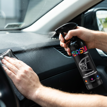 Ręka spryskuje deskę rozdzielczą samochodu czarnym płynem EASY Interior Cleaner, druga ręka wyciera szarą ściereczką.