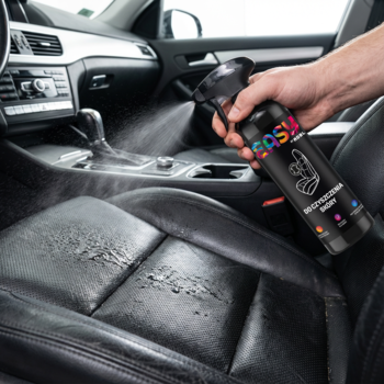 Ręka spryskuje czarny, skórzany fotel w aucie czarnym sprayem Easy do czyszczenia wnętrza, widok z boku.